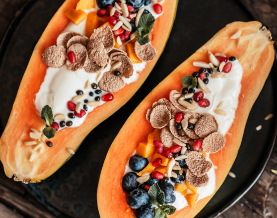 papaya cut in half lengthwise filled with yogurt and topped with fruit and granola