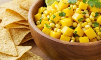 mango and corn salsa with cilantro and lime wedges alongside corn tortilla chips