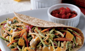chicken tacos topped with broccoli slaw and peaches in a creamy dressing