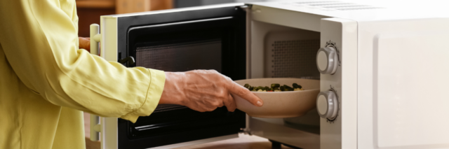 woman placing vegetables in microwave