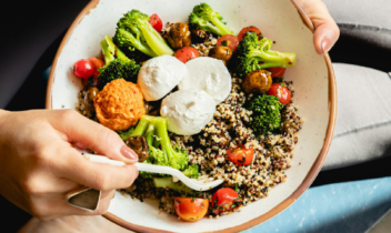 woman sitting and eating a grain bowl