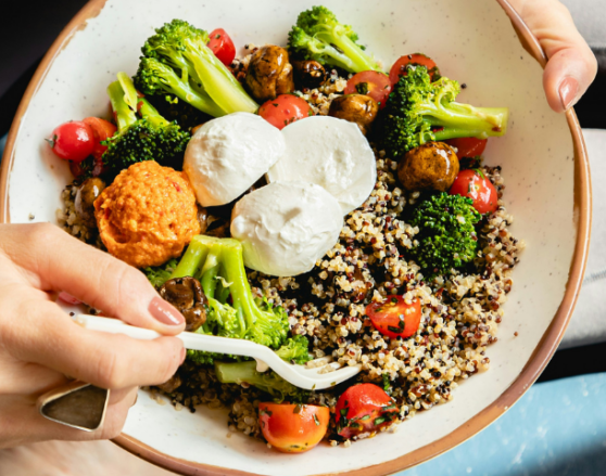 woman sitting and eating a grain bowl