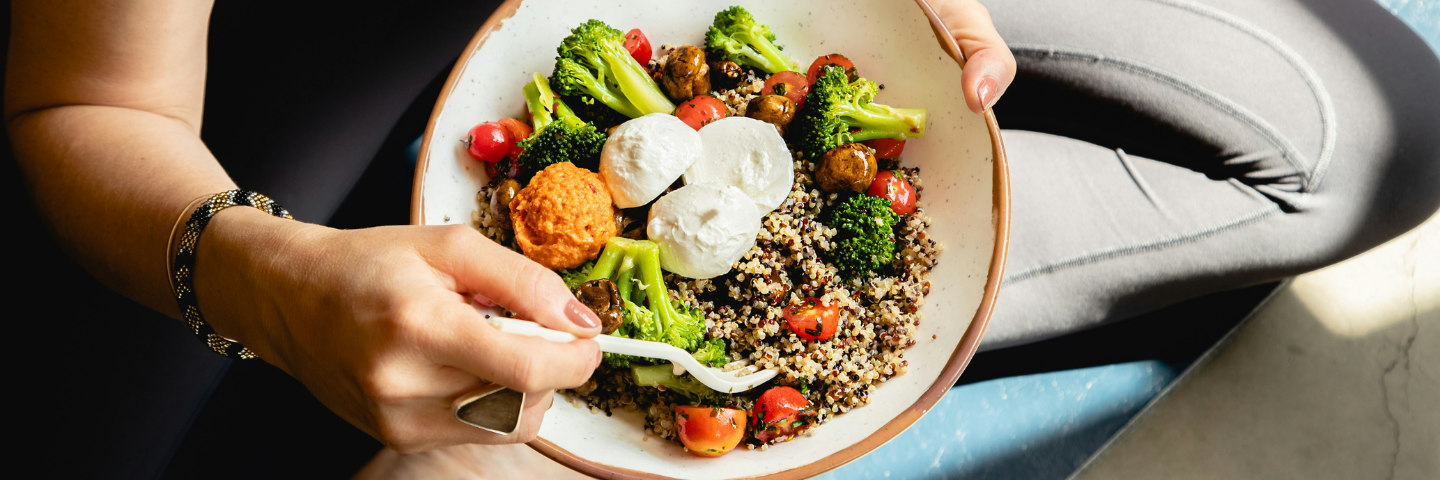 woman sitting and eating a grain bowl