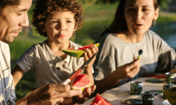 family eating watermelon by a lake