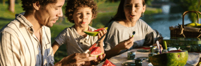 family eating watermelon by a lake