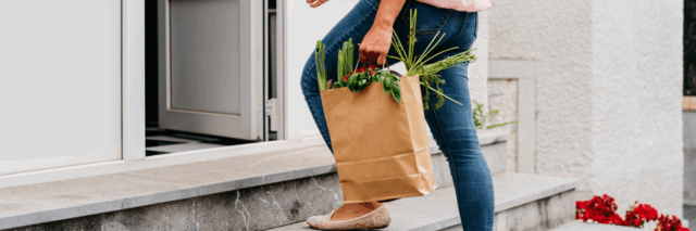 woman carrying paper grocery bag with produce