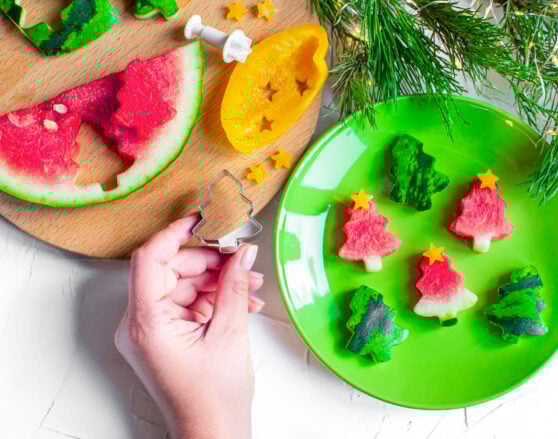 person holding a christmas tree cookie cutter and watermelon