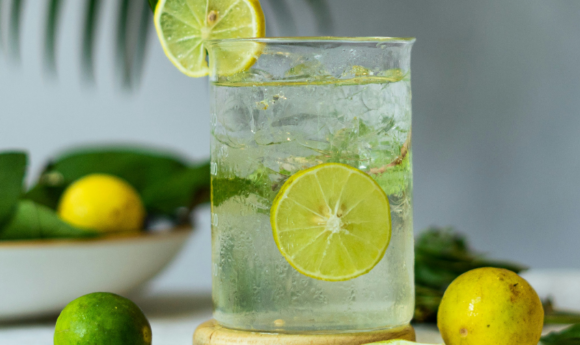 glass of water with ice and slices of lemons and limes