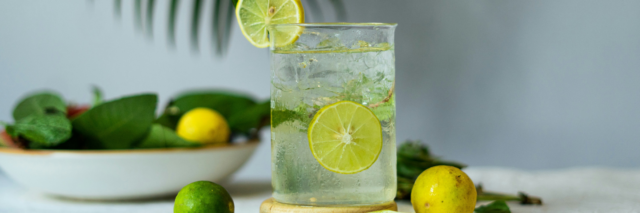 glass of water with ice and slices of lemons and limes