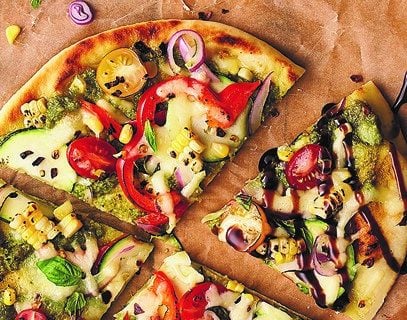 naan flatbread topped with mozzarella cheese and garden fresh veggies topped with a balsamic glaze drizzle