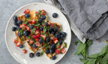 grilled halloumi cheese topped with strawberries blueberries and mint leaves
