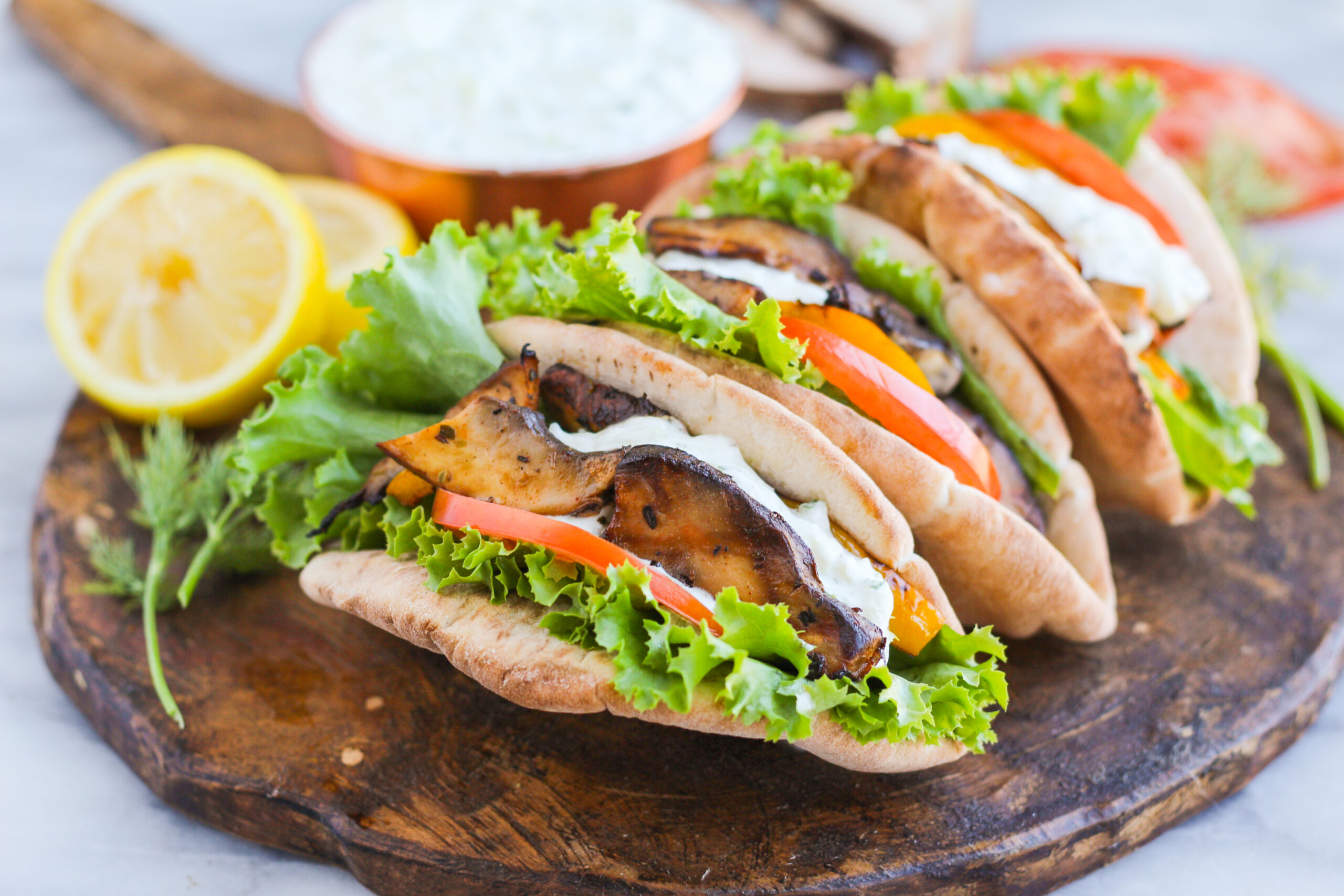 grilled portabella mushrooms in a pita with lettuce tomato and tzatziki sauce drizzled on top
